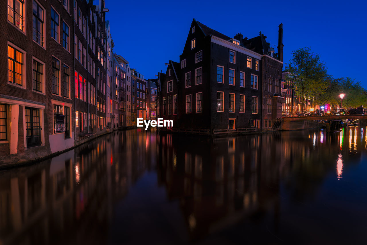 Canal amidst buildings at night