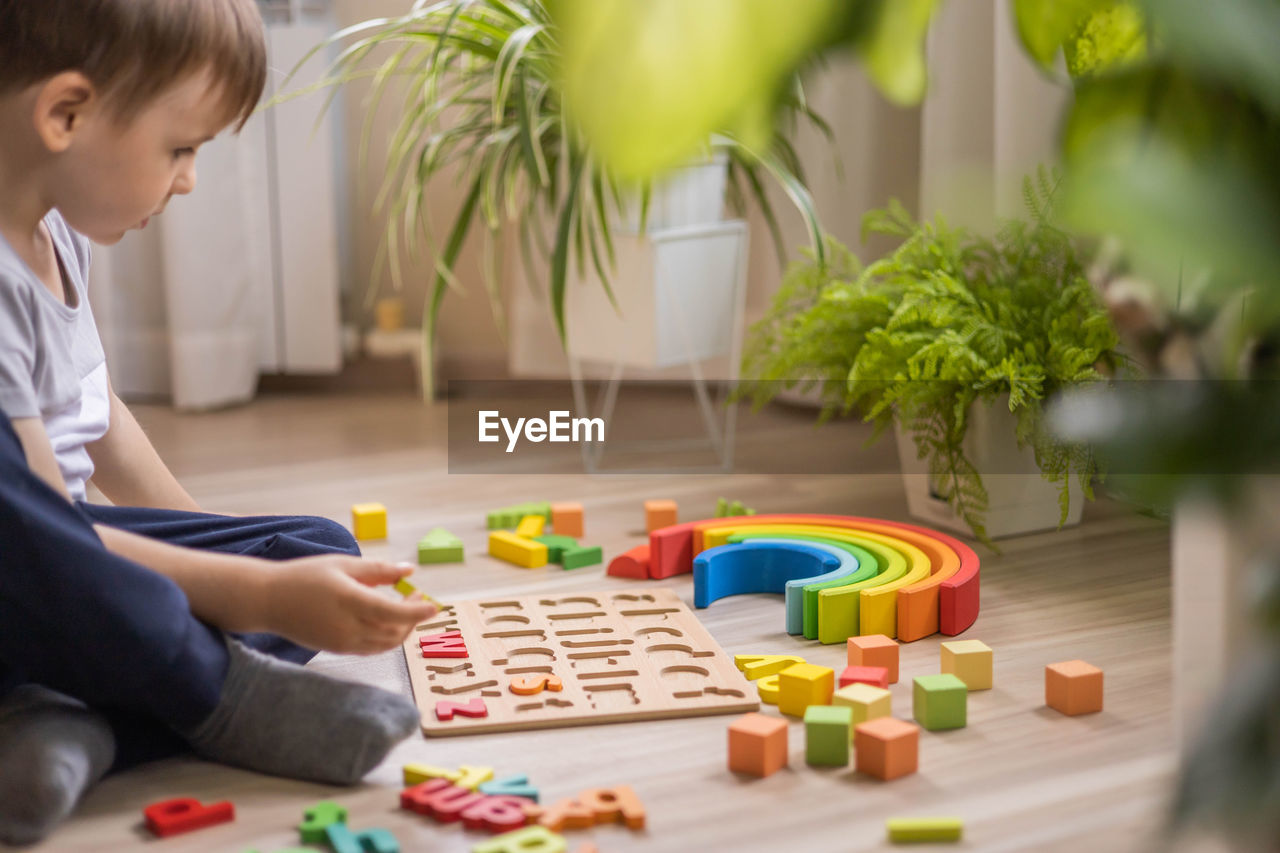 midsection of boy playing with toy blocks on table