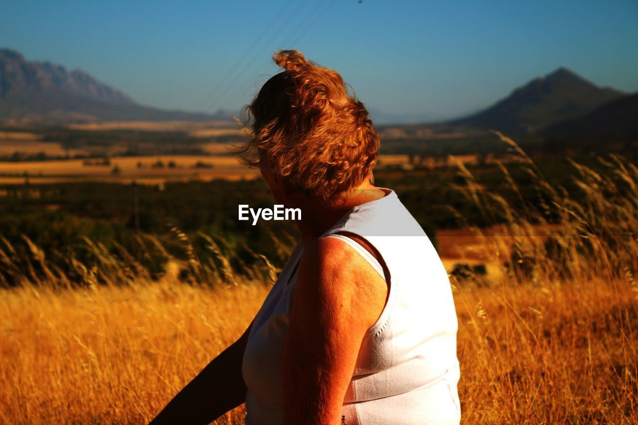 Woman sitting on field against sky during sunset