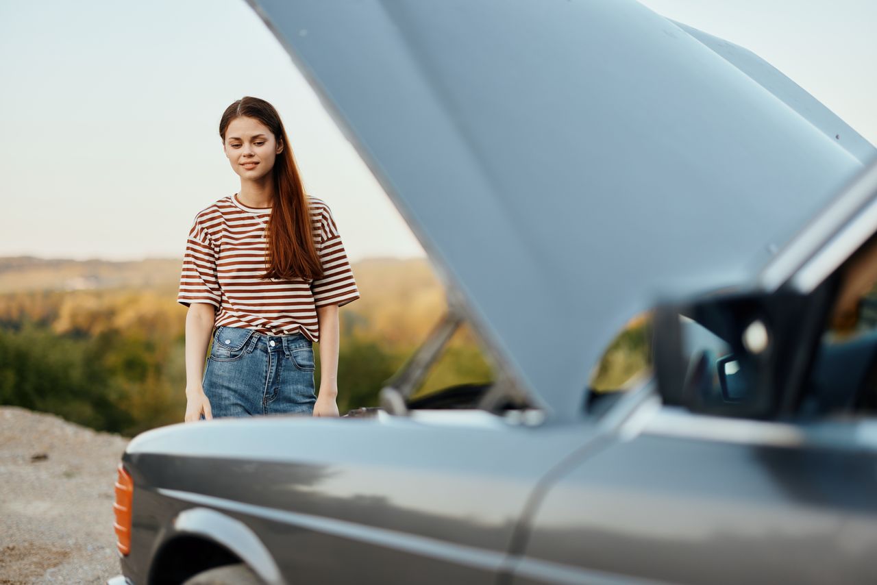 side view of young woman holding car on road