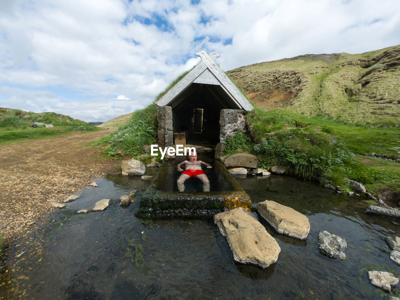 Man relaxing in a small geothermal hot spring pool in hrunalaug, iceland