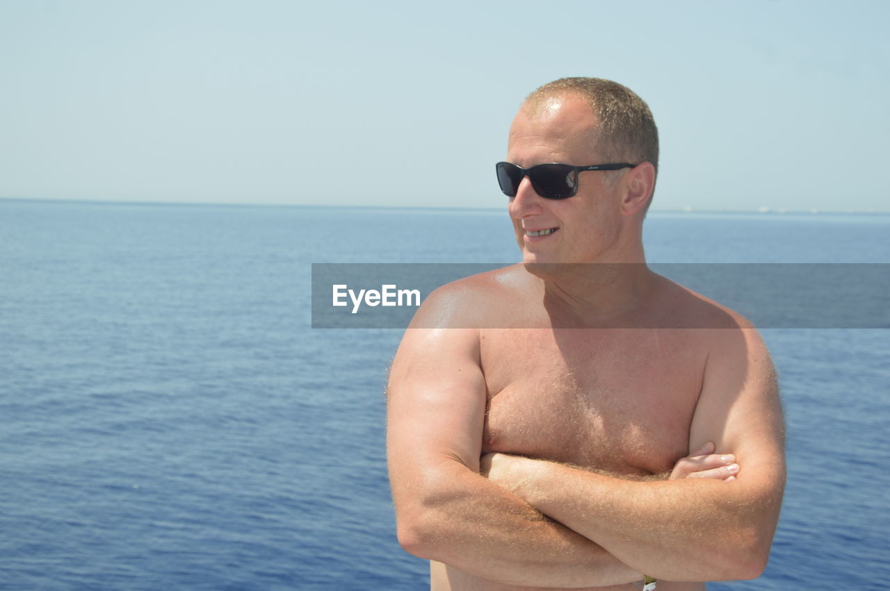 MAN WEARING SUNGLASSES AGAINST SEA