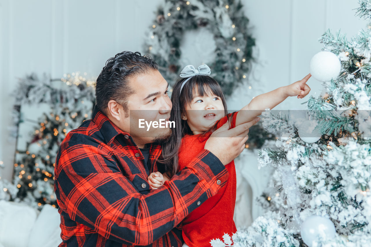 Father and daughter looking at christmas tree at home