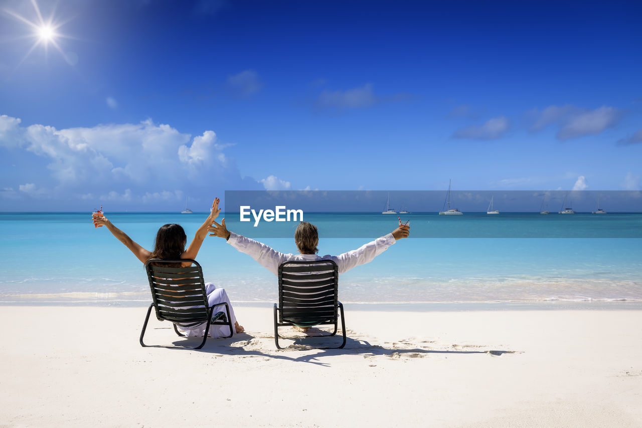 rear view of woman standing at beach against sky