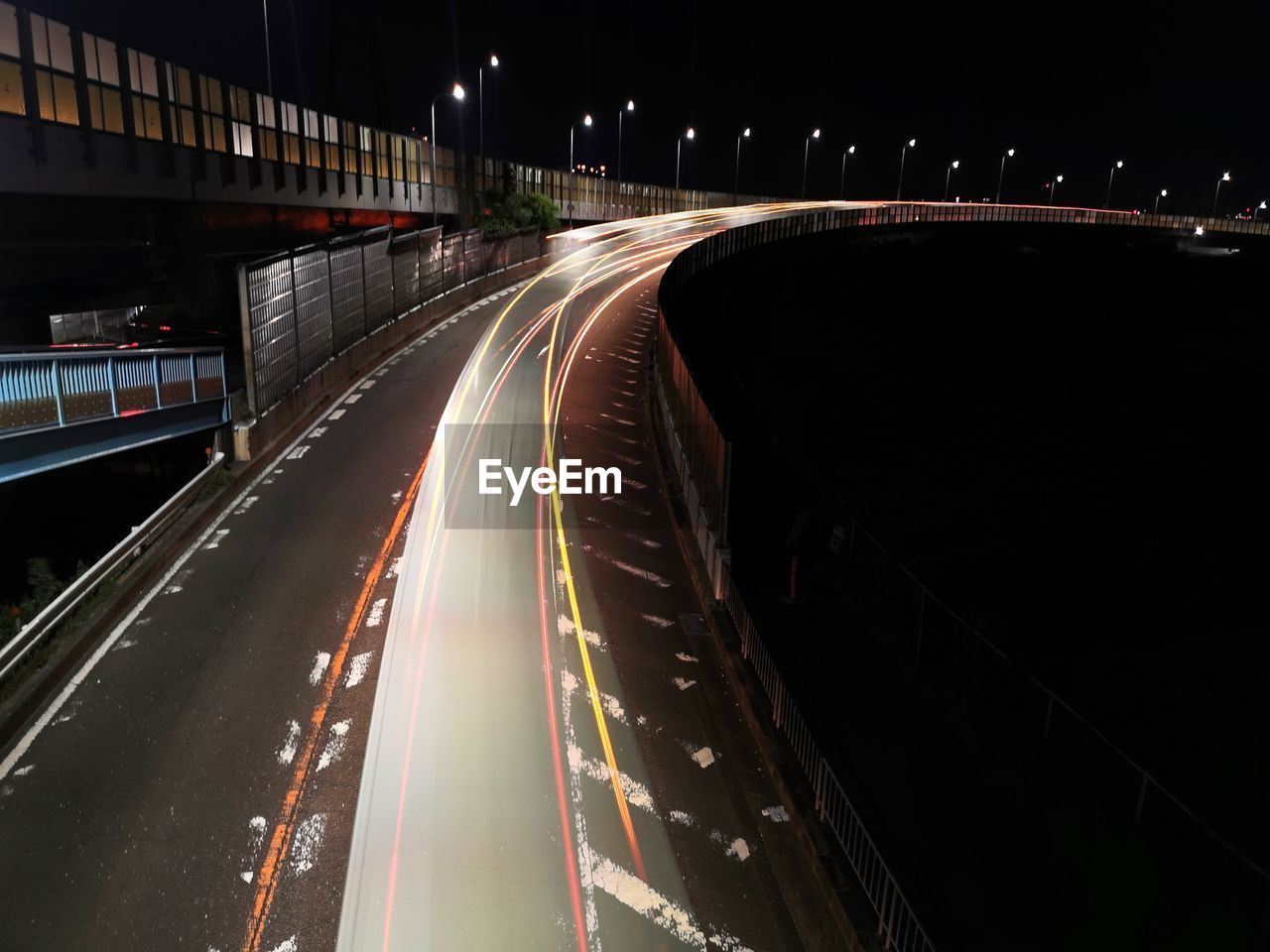 transportation, night, light trail, illuminated, long exposure, road, architecture, speed, motion, city, traffic, highway, built structure, street, mode of transportation, tail light, darkness, blurred motion, city life, motor vehicle, no people, lane, car, infrastructure, building exterior, street light, light, lighting equipment, headlight, bridge, outdoors, high angle view, multiple lane highway, city street, light - natural phenomenon, sign, the way forward, nature, overpass, vehicle light, on the move, travel, cityscape, sky