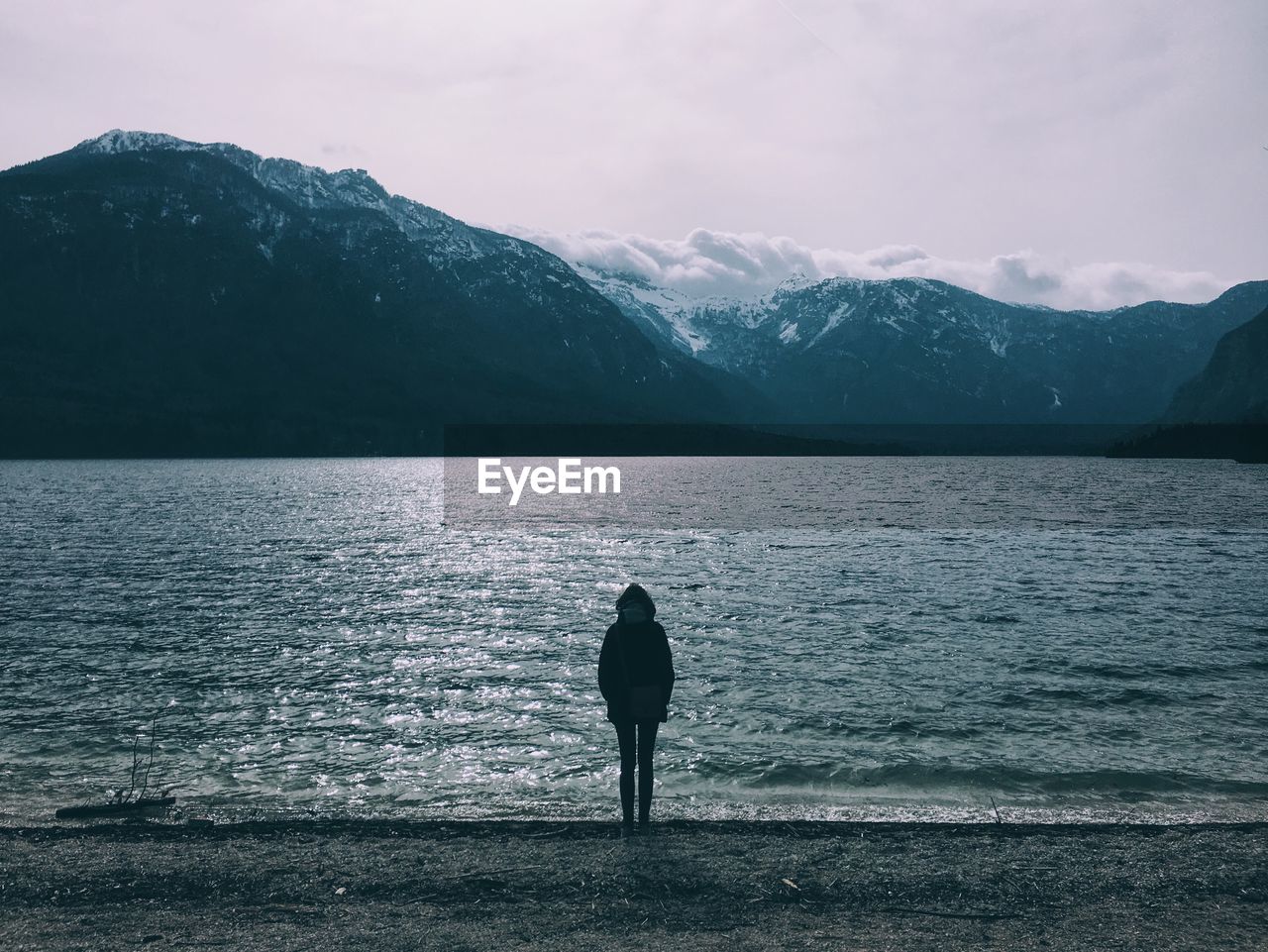 Rear view of silhouette person on lake against mountains