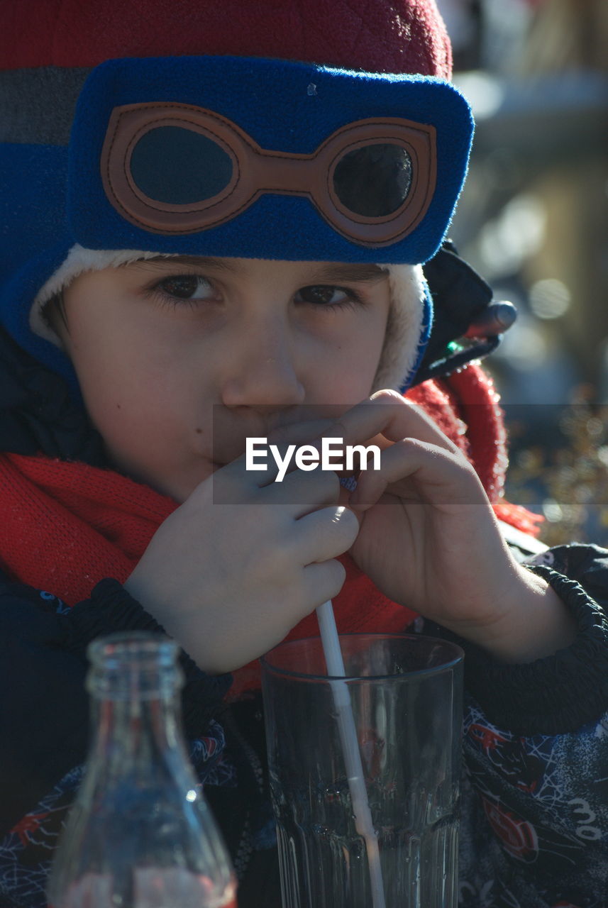 PORTRAIT OF CUTE BOY DRINKING FROM SUNGLASSES