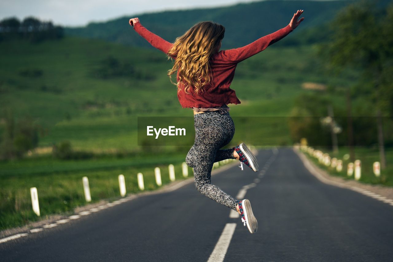 Young woman jumping on road