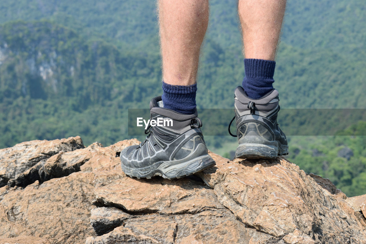 Low section of man standing on mountain peak
