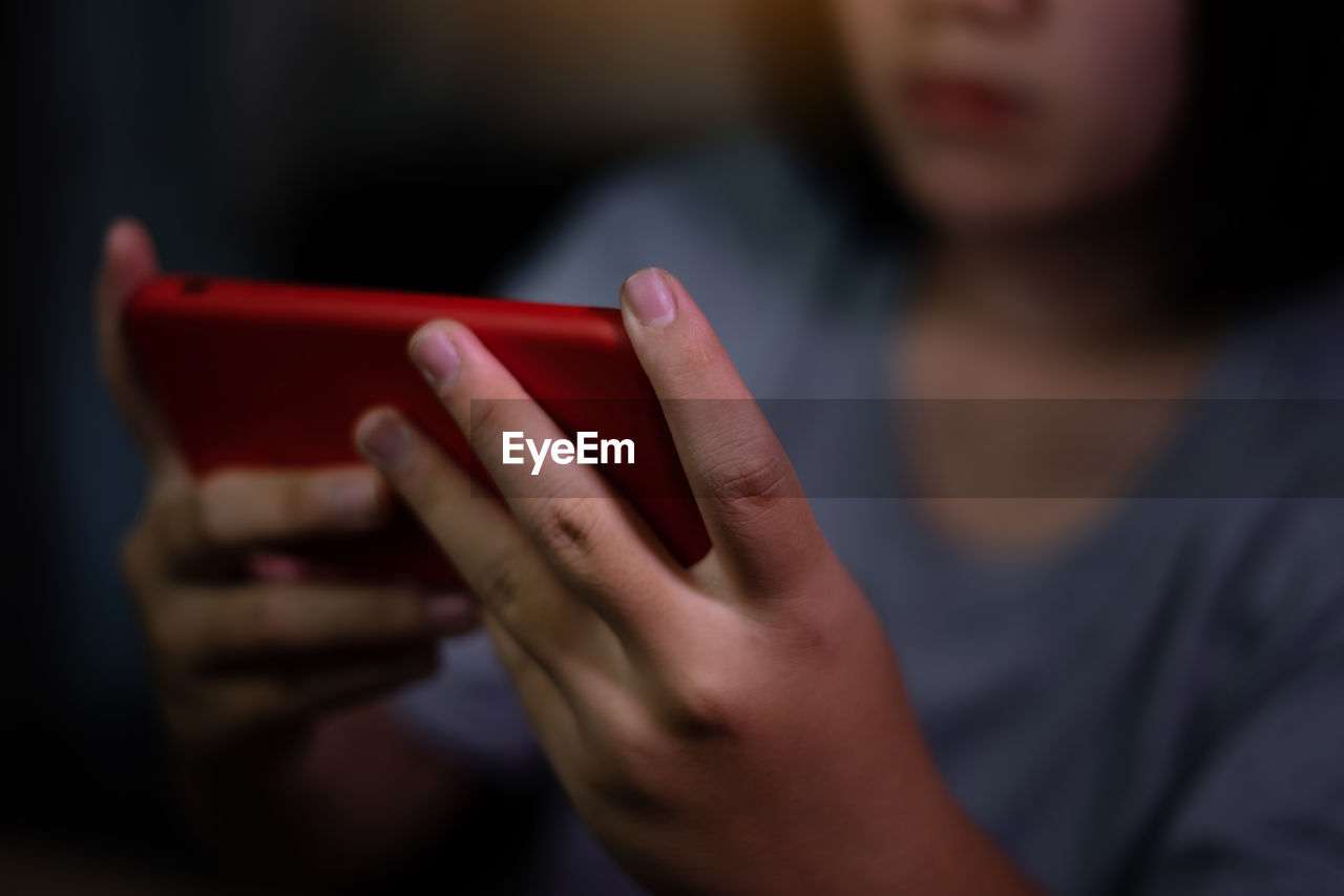 CLOSE-UP OF HUMAN HAND HOLDING RED SMART PHONE