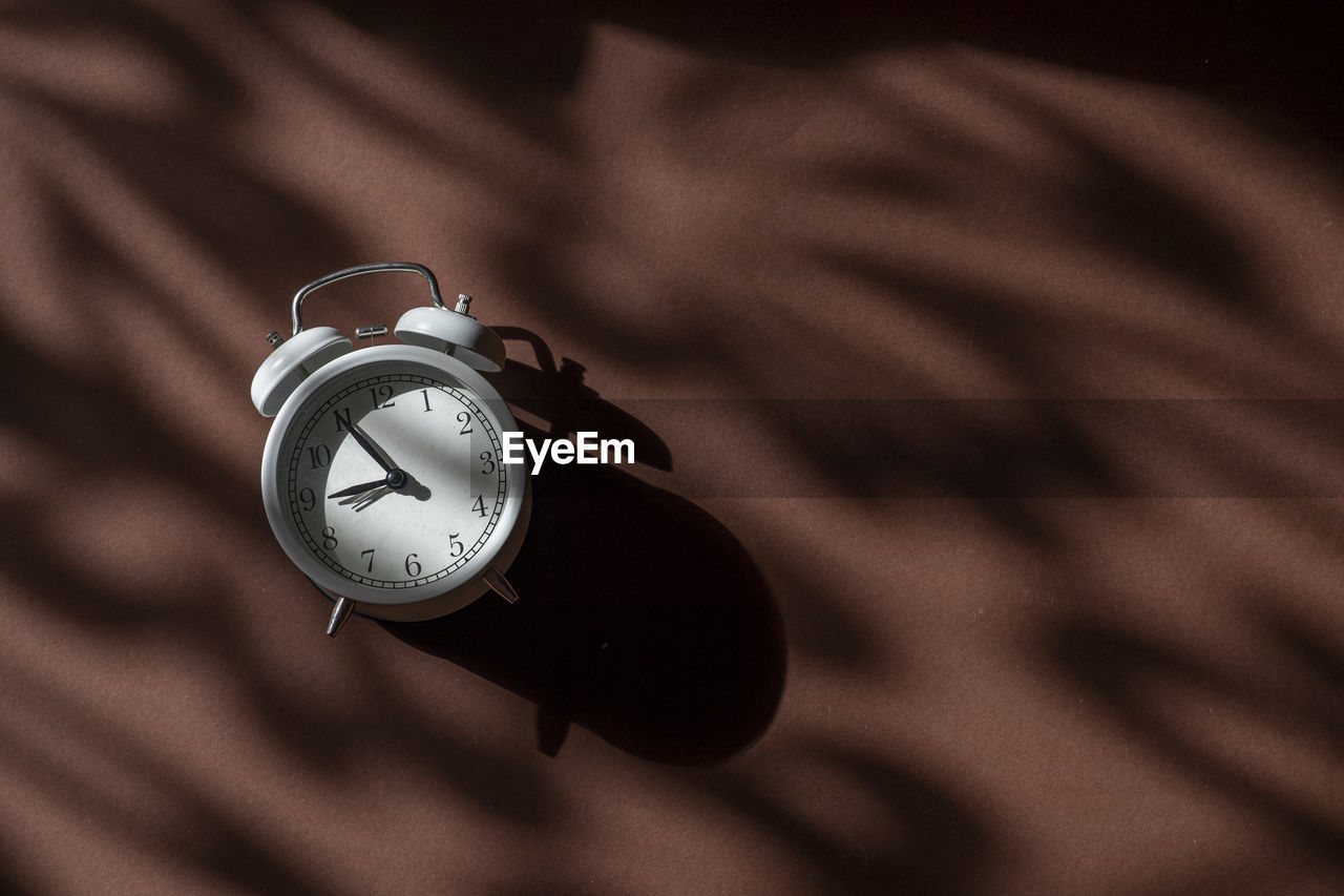 High angle view of clock on brown background