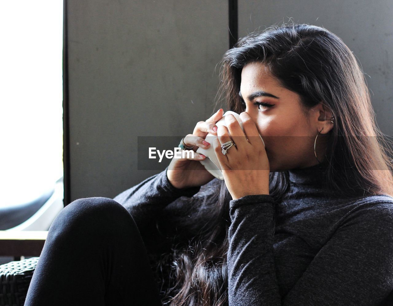 Thoughtful young woman holding coffee cup in cafe