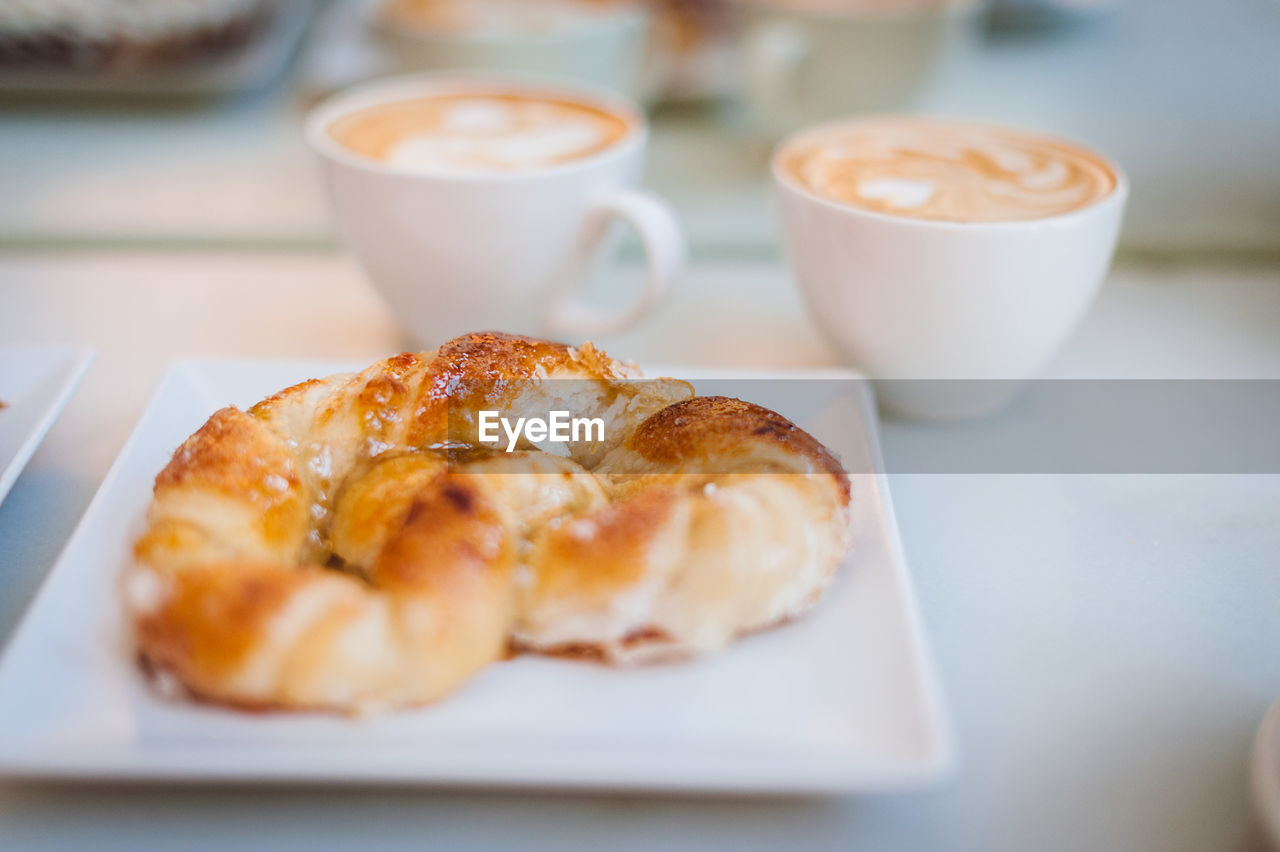 High angle view of croissant with cappuccinos served on table