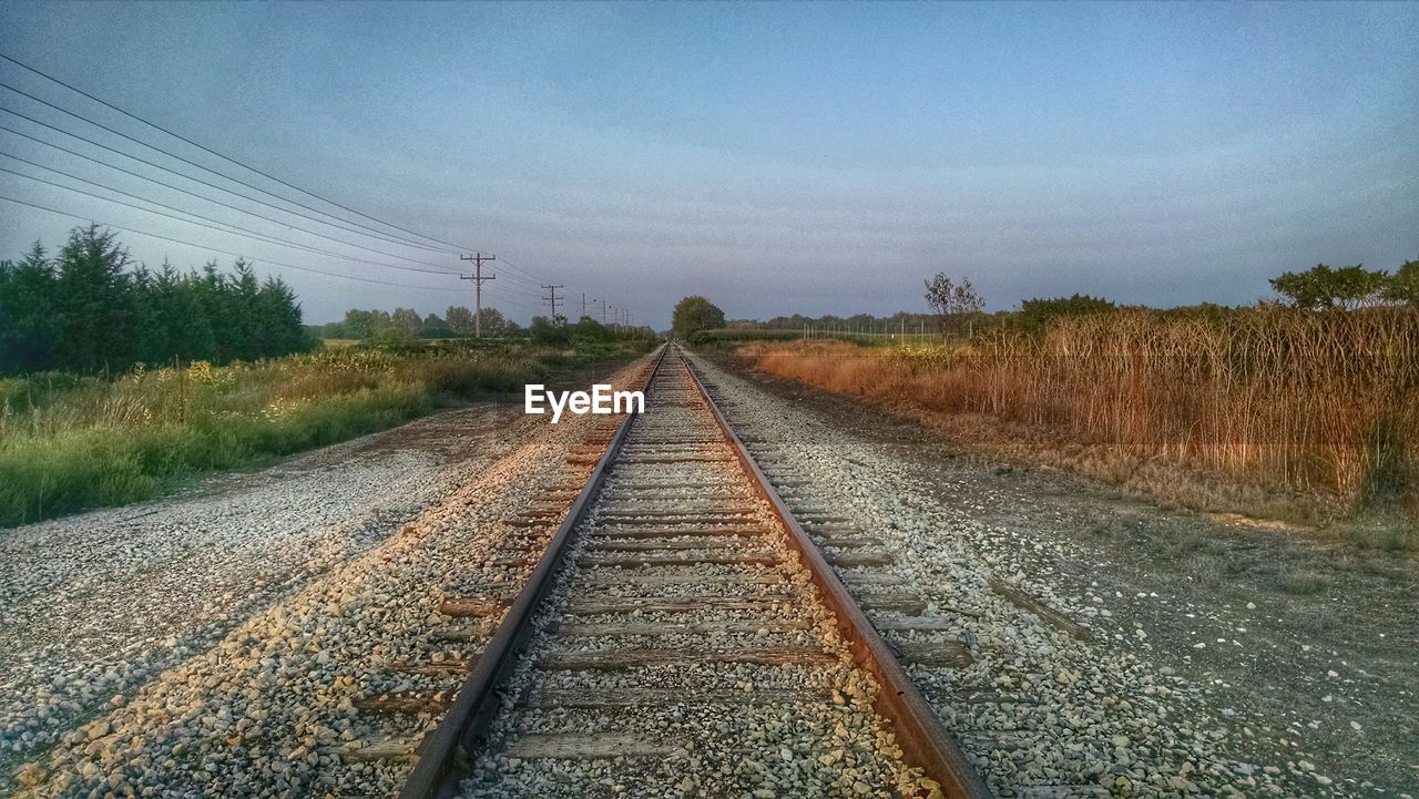 Railroad tracks amidst field against sky