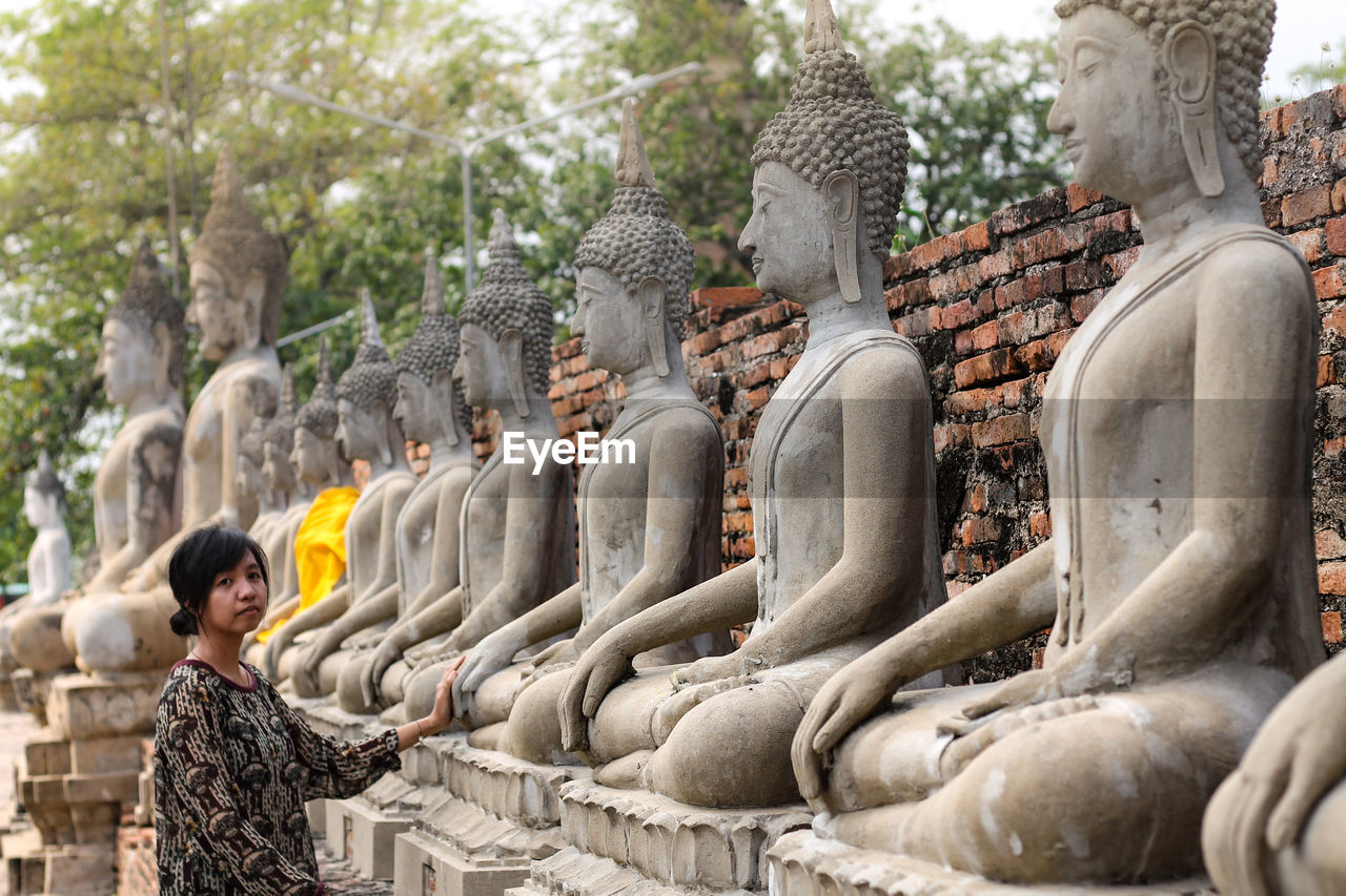 Portrait of mid adult woman standing by buddha statues