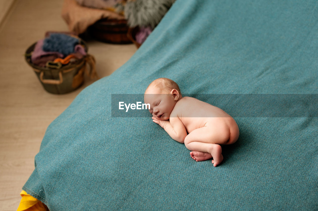 HIGH ANGLE VIEW OF CUTE BABY SLEEPING IN BED