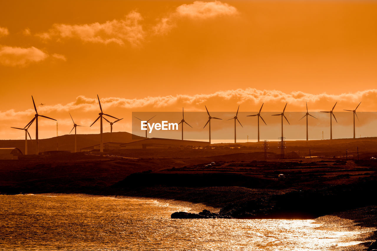 WIND TURBINES ON LAND DURING SUNSET