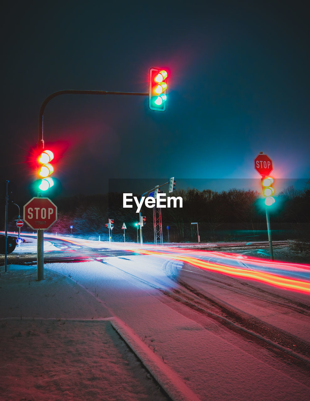 Stop light and light trail on the snow covered road at night