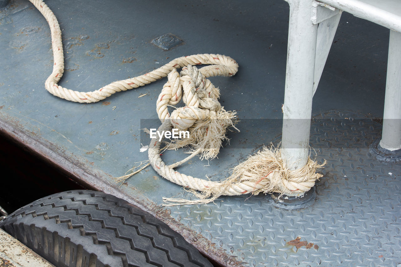 High angle view of rope tied to metal on footpath