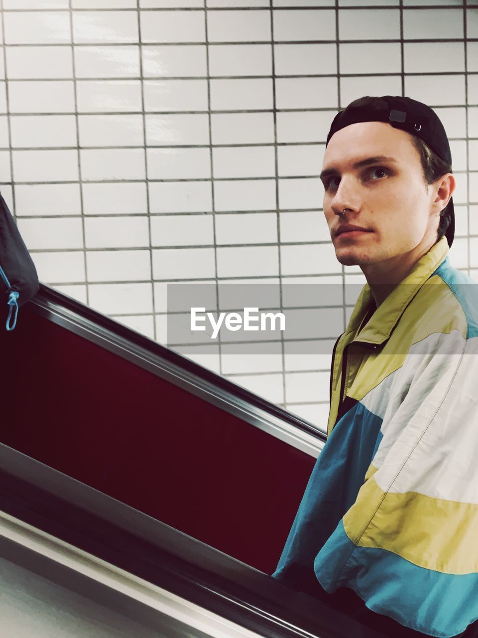 Portrait of young man standing on escalator