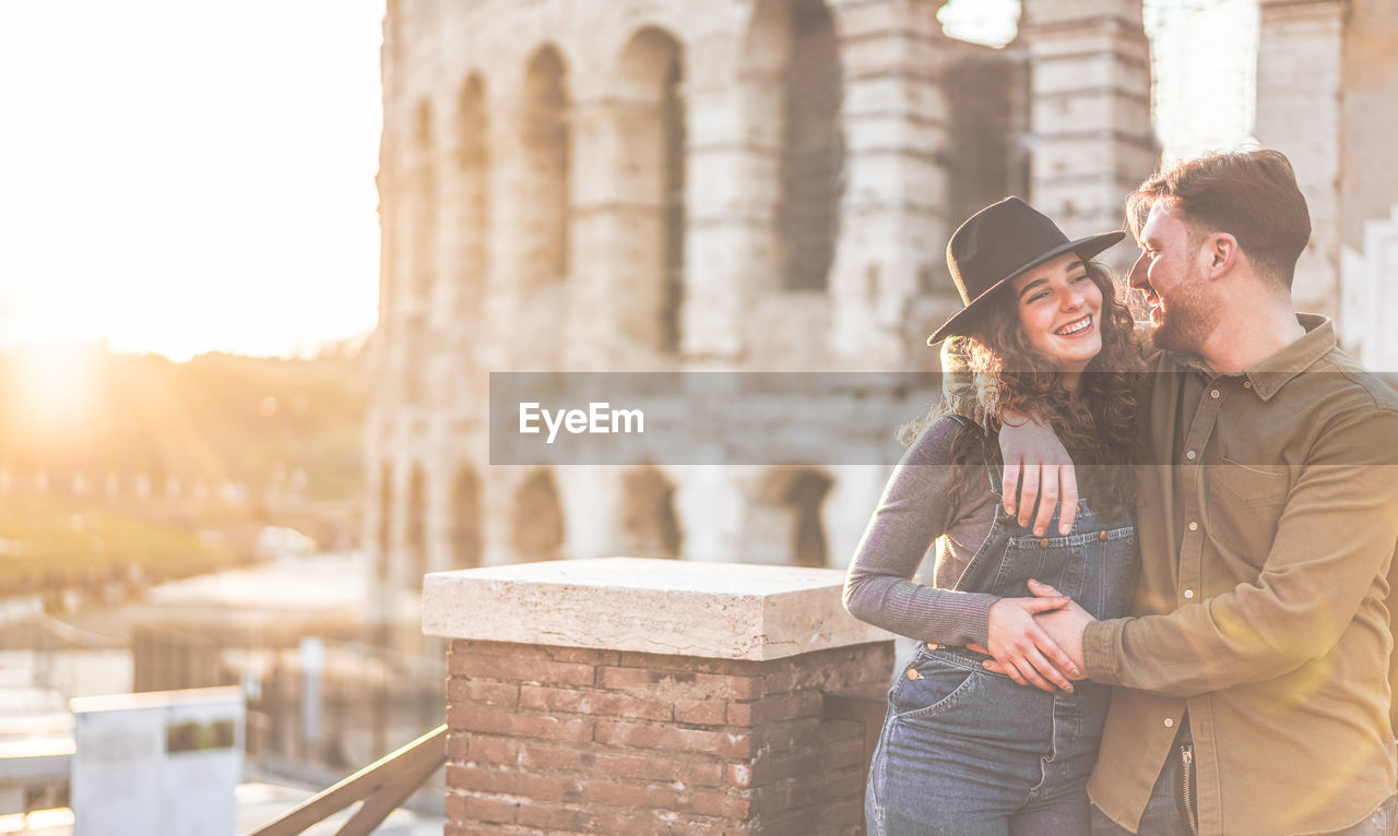 Romantic young couple standing against coliseum