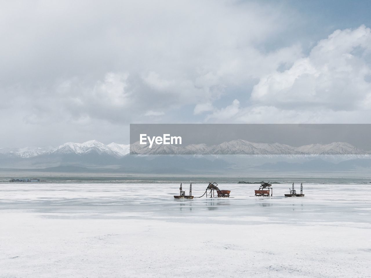 Machinery on salt lake against sky during winter