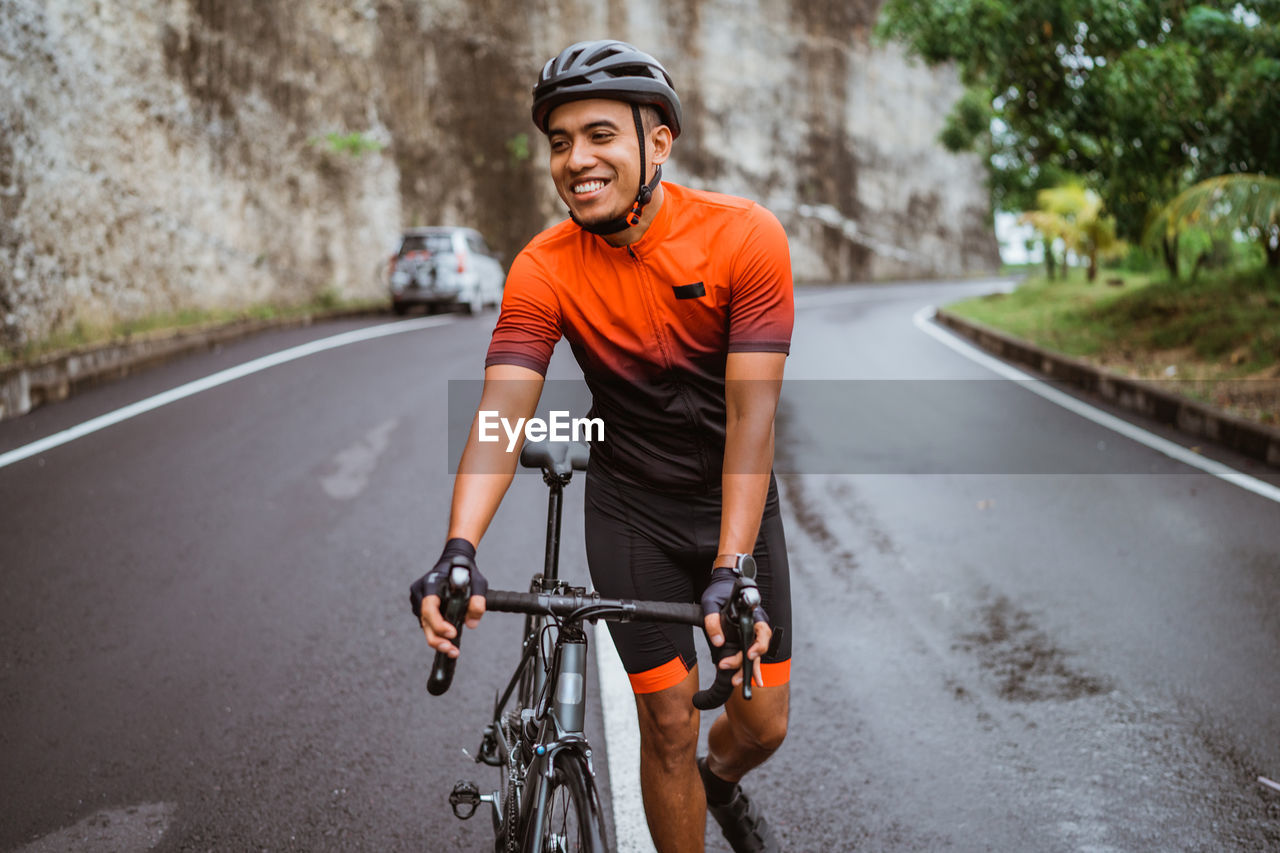 Man wheeling with bicycle on road