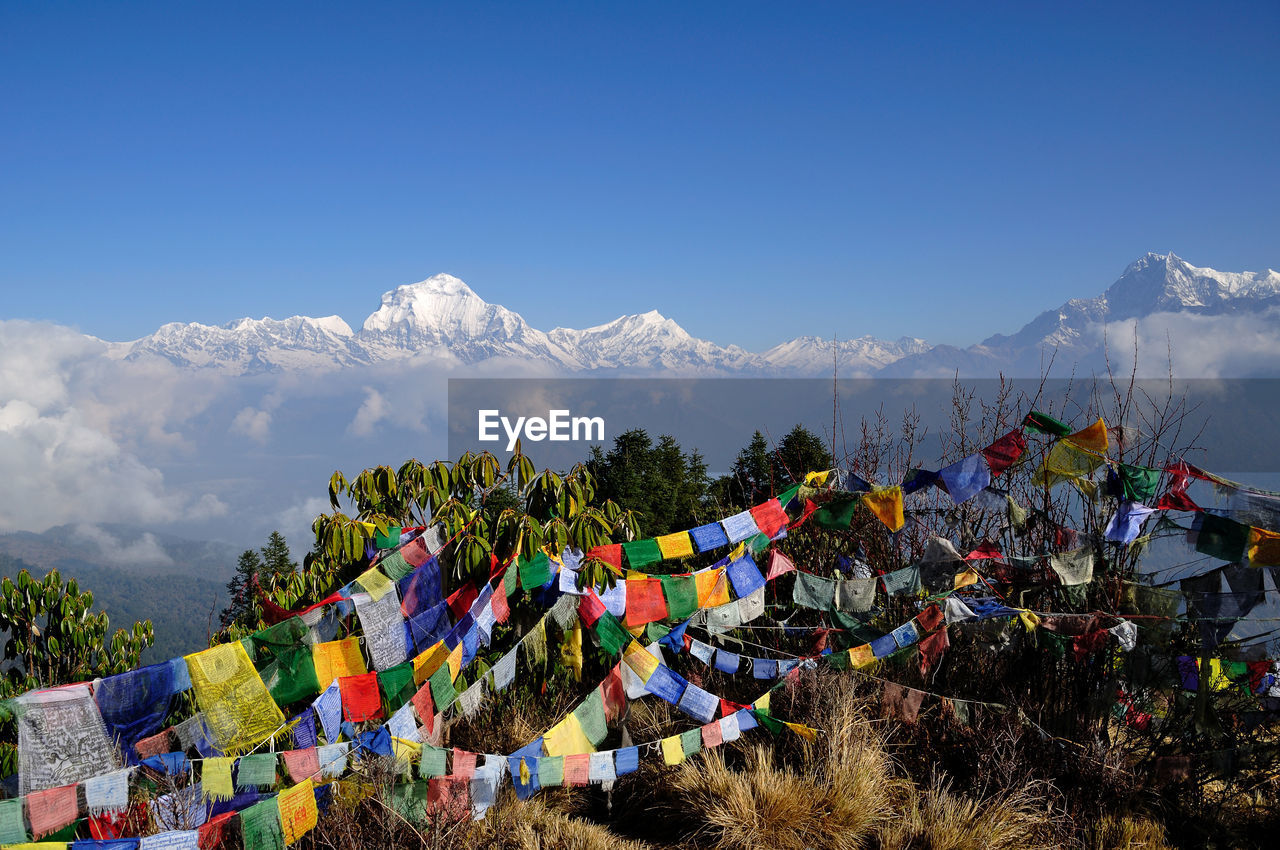 Prayer flags hanging over mountain against sky during winter