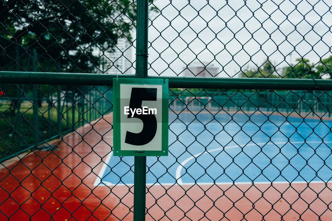 Close-up of number on chainlink fence at court