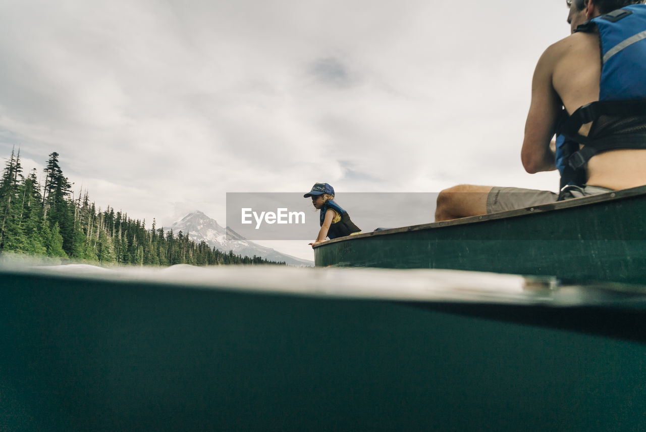 A young girl rides in a canoe with her dad on lost lake in oregon.