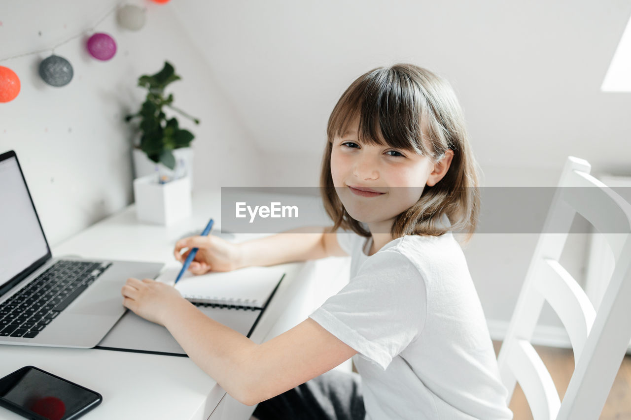 portrait of young woman using laptop while sitting on table