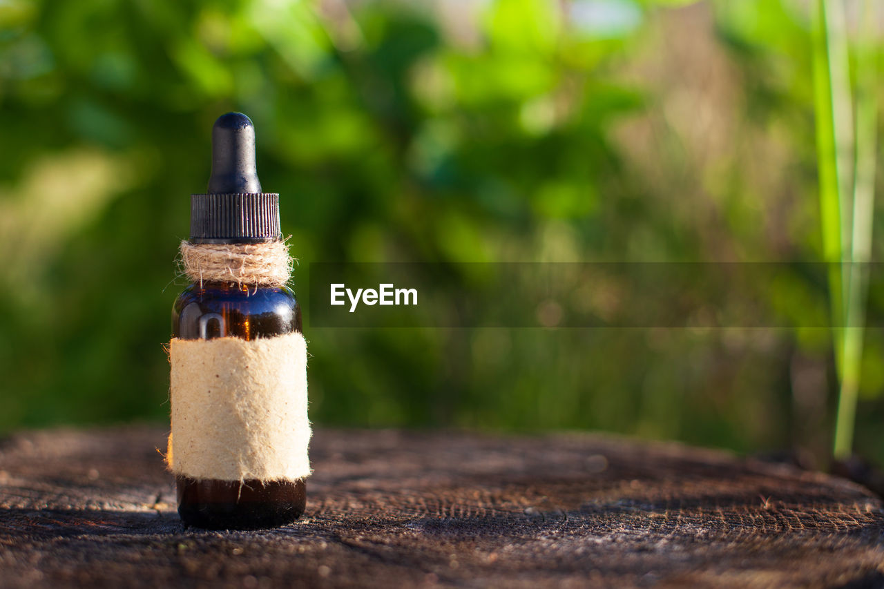 CLOSE-UP OF DRINK ON TABLE AGAINST TREE