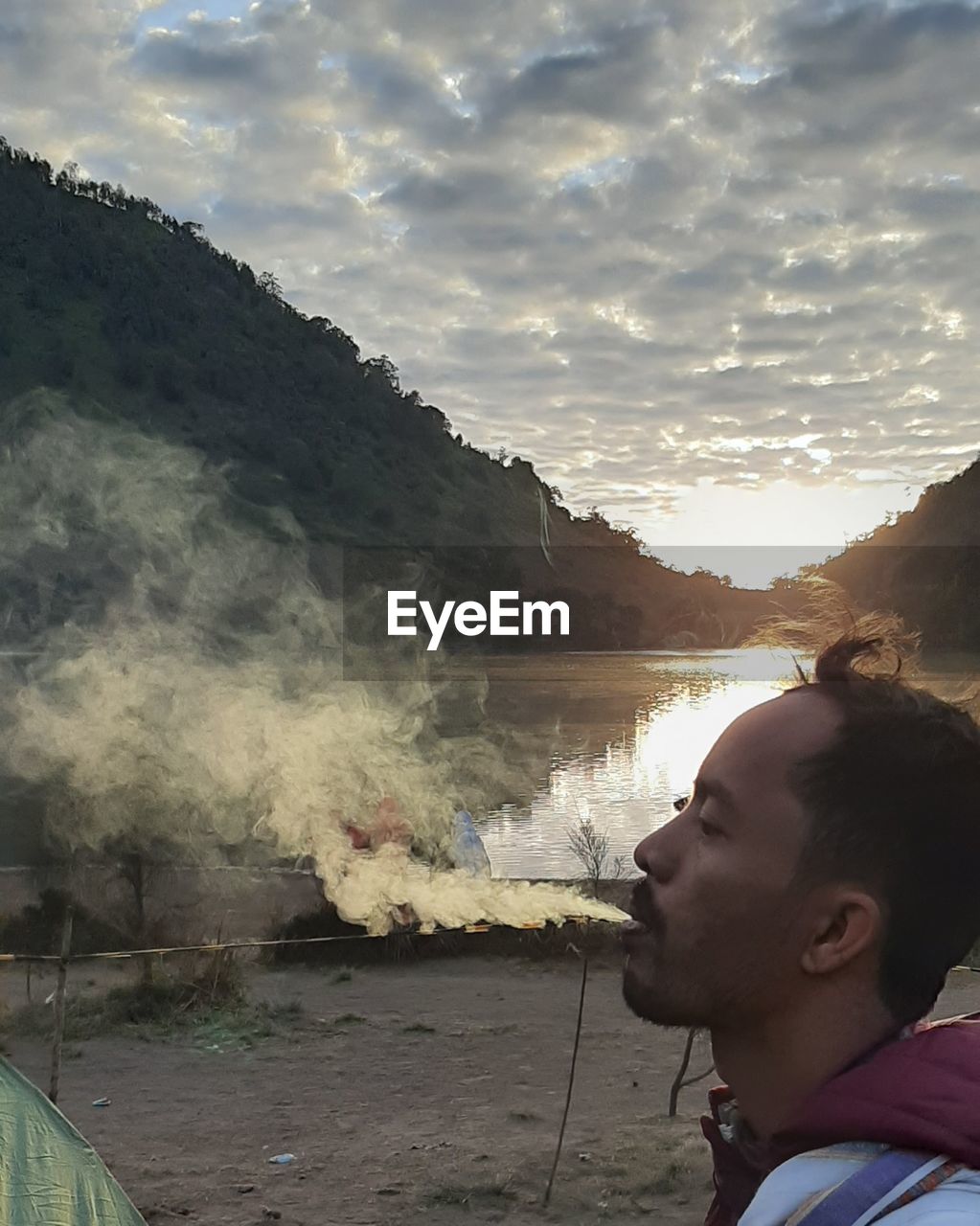 SIDE VIEW PORTRAIT OF YOUNG MAN AGAINST MOUNTAINS
