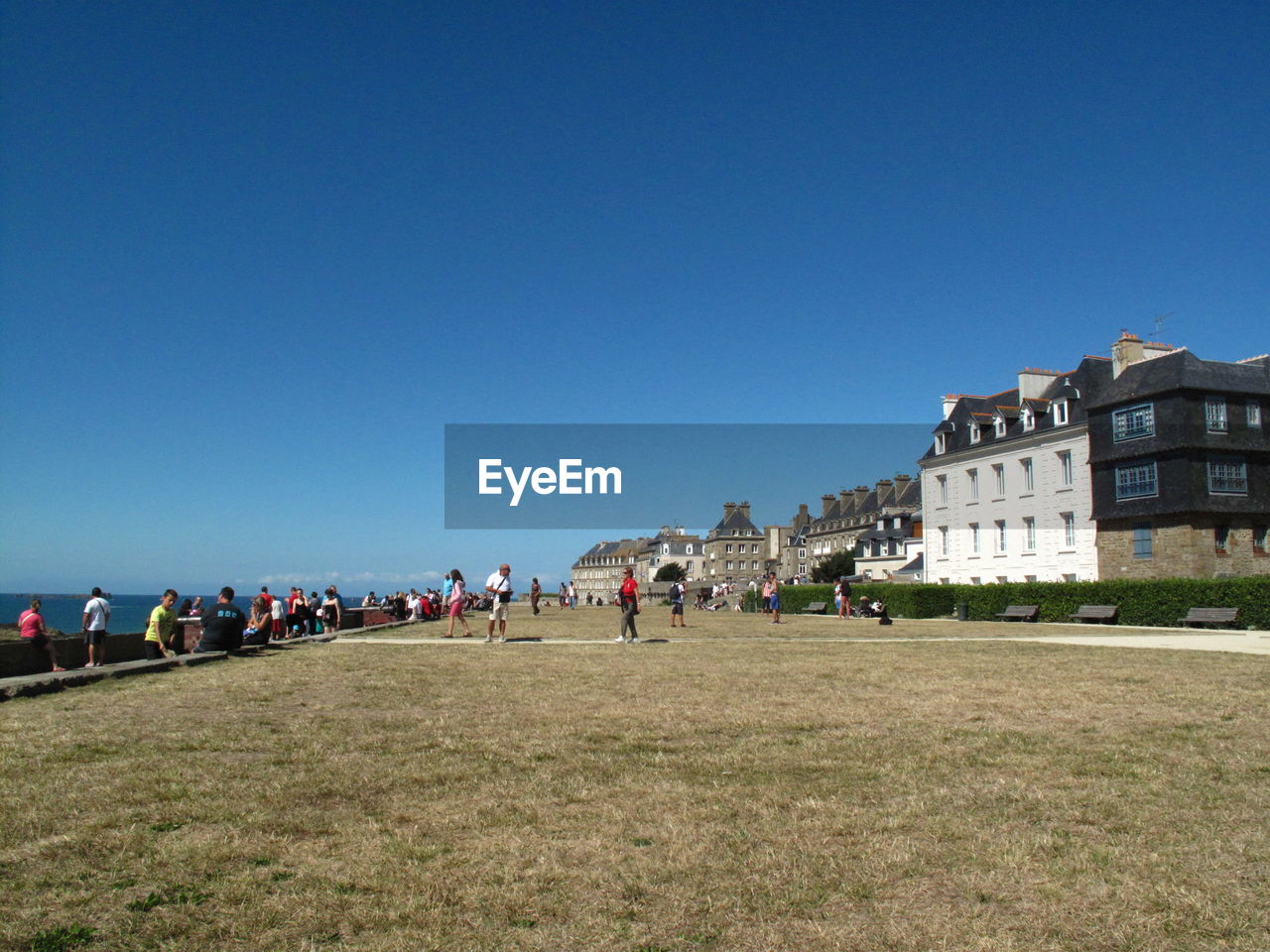 People on field against clear blue sky at brittany
