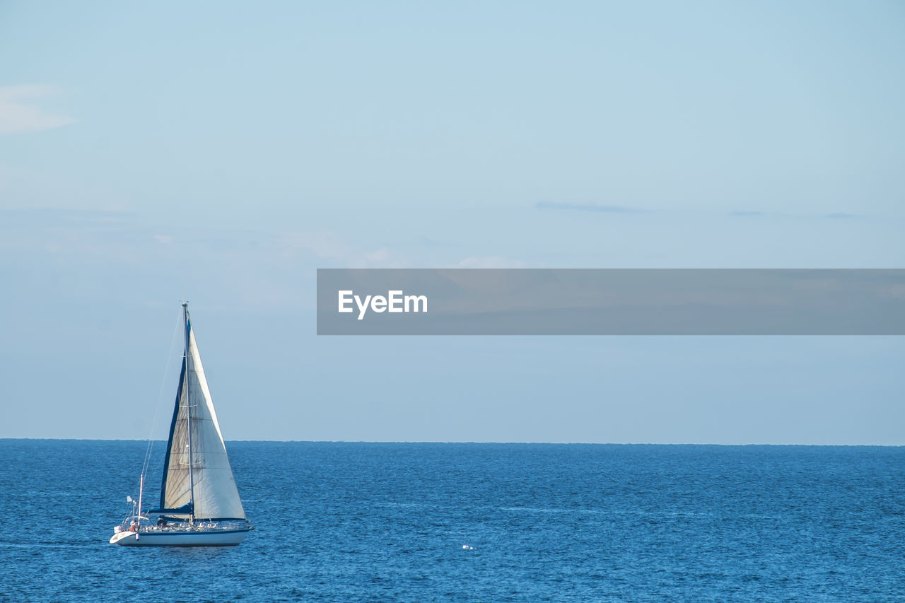 Sailboat sailing on sea against sky