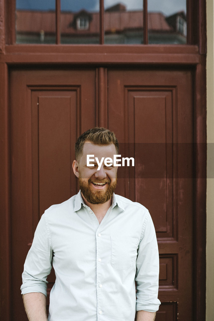 Smiling man standing against door