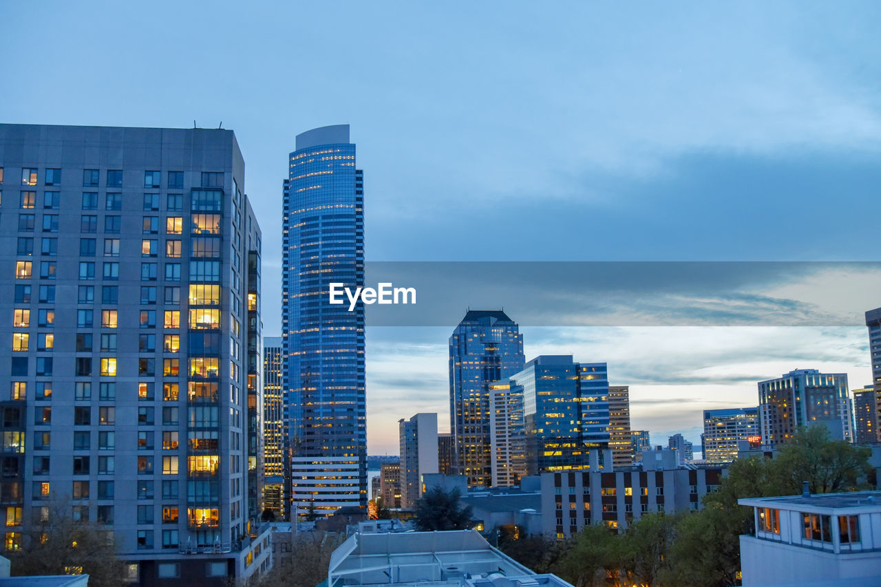 Modern buildings in city against sky at dusk