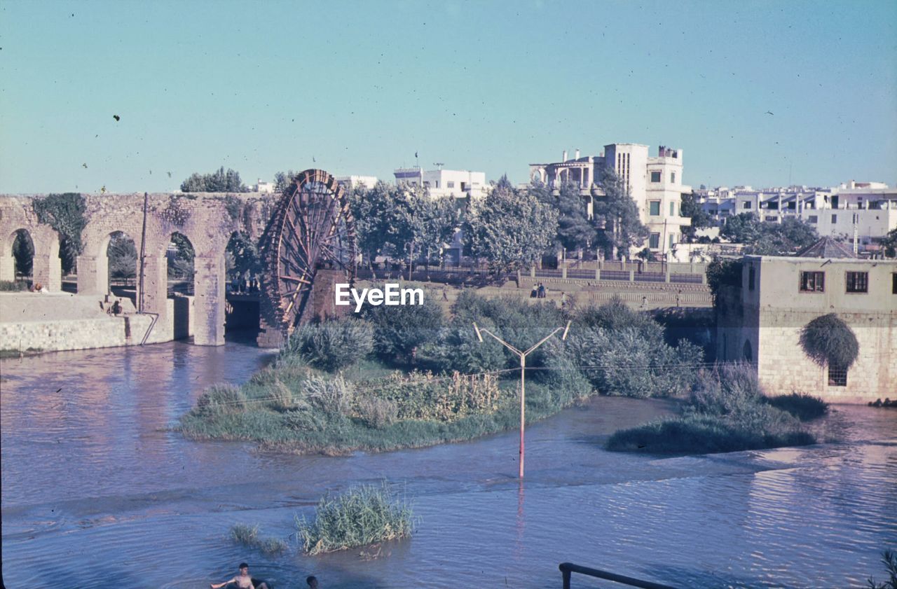 ARCH BRIDGE OVER RIVER BY BUILDINGS AGAINST SKY