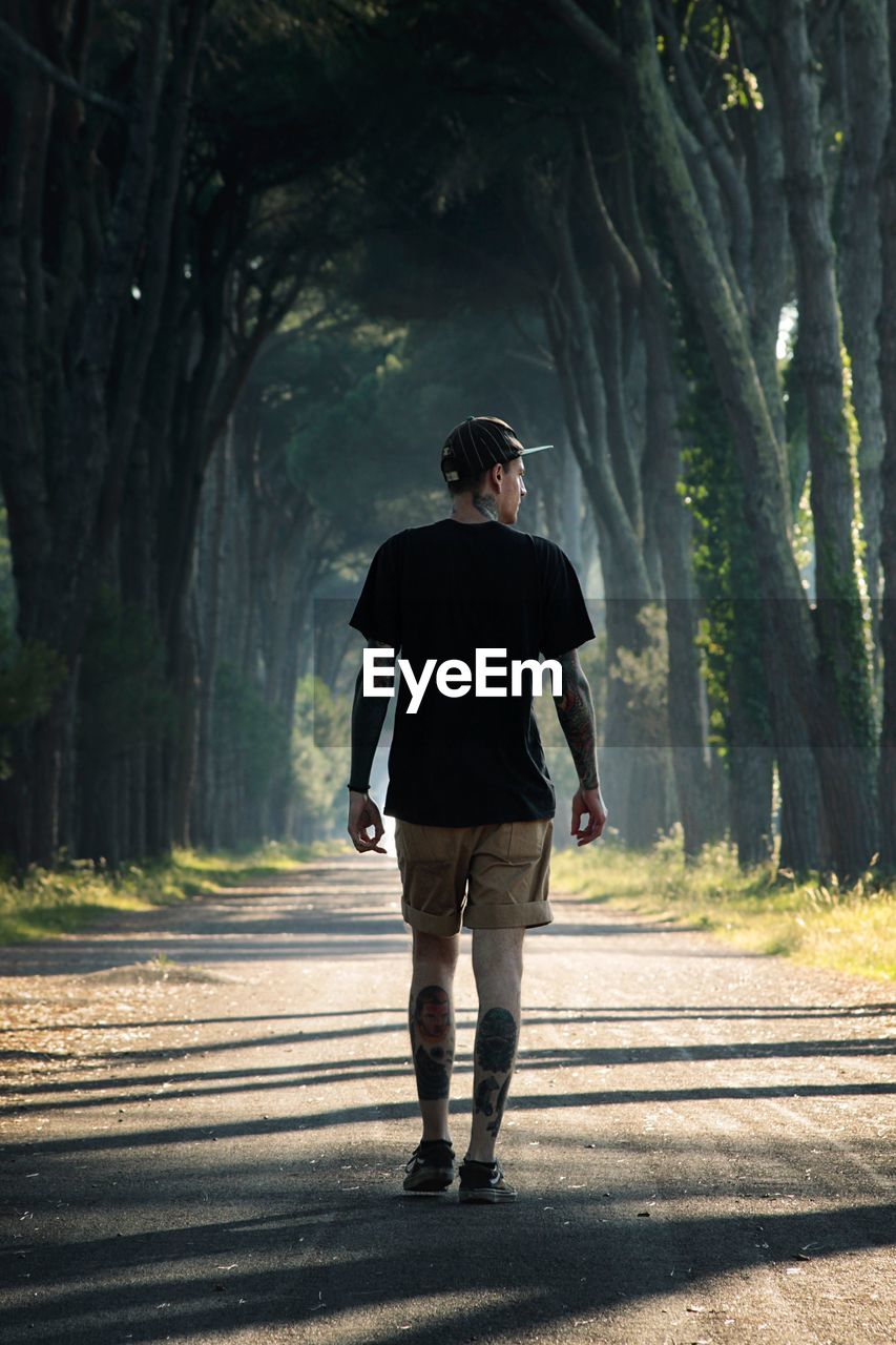 Rear view of man walking on road in forest