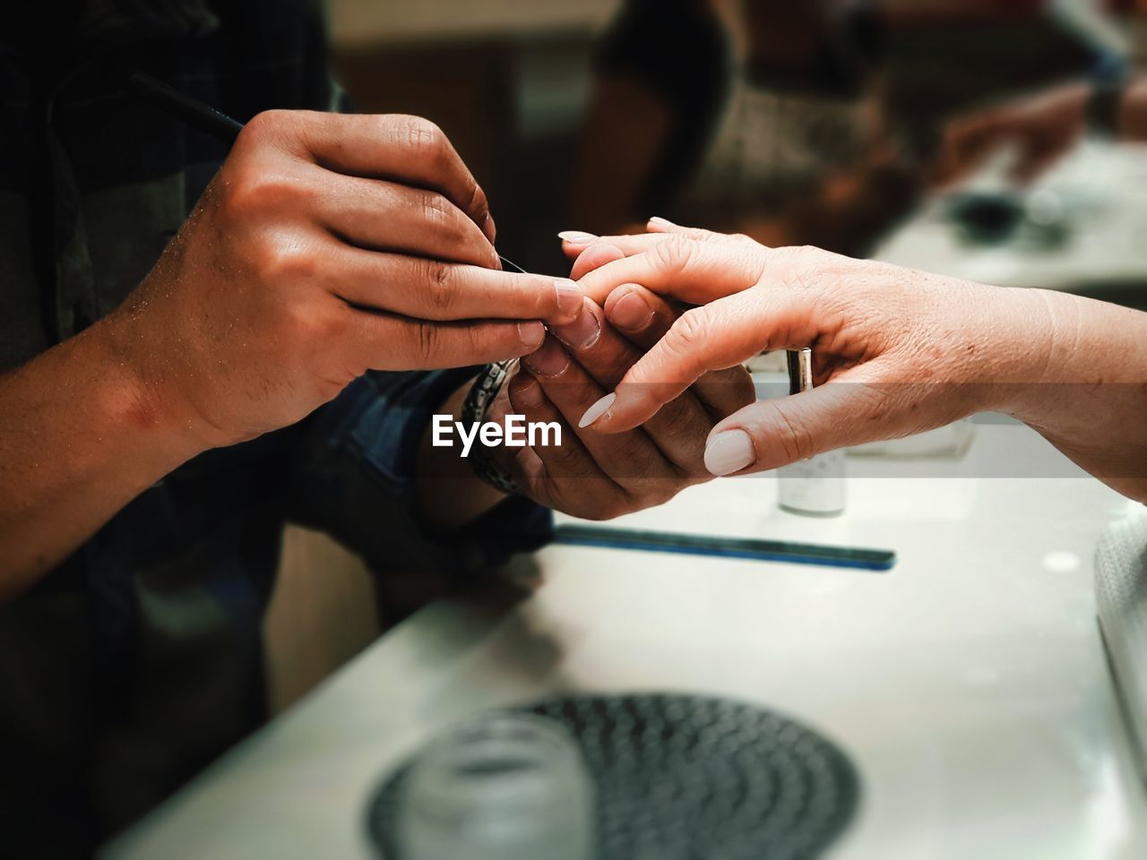 Midsection of man giving manicure to woman