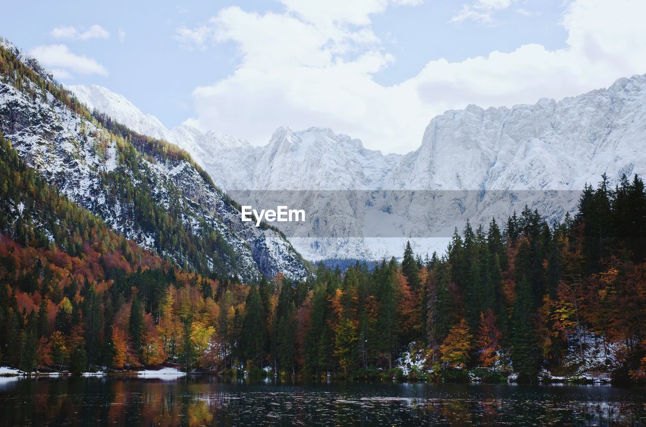 Scenic view of the snow covered mountains against the autumn forest and italian lake.