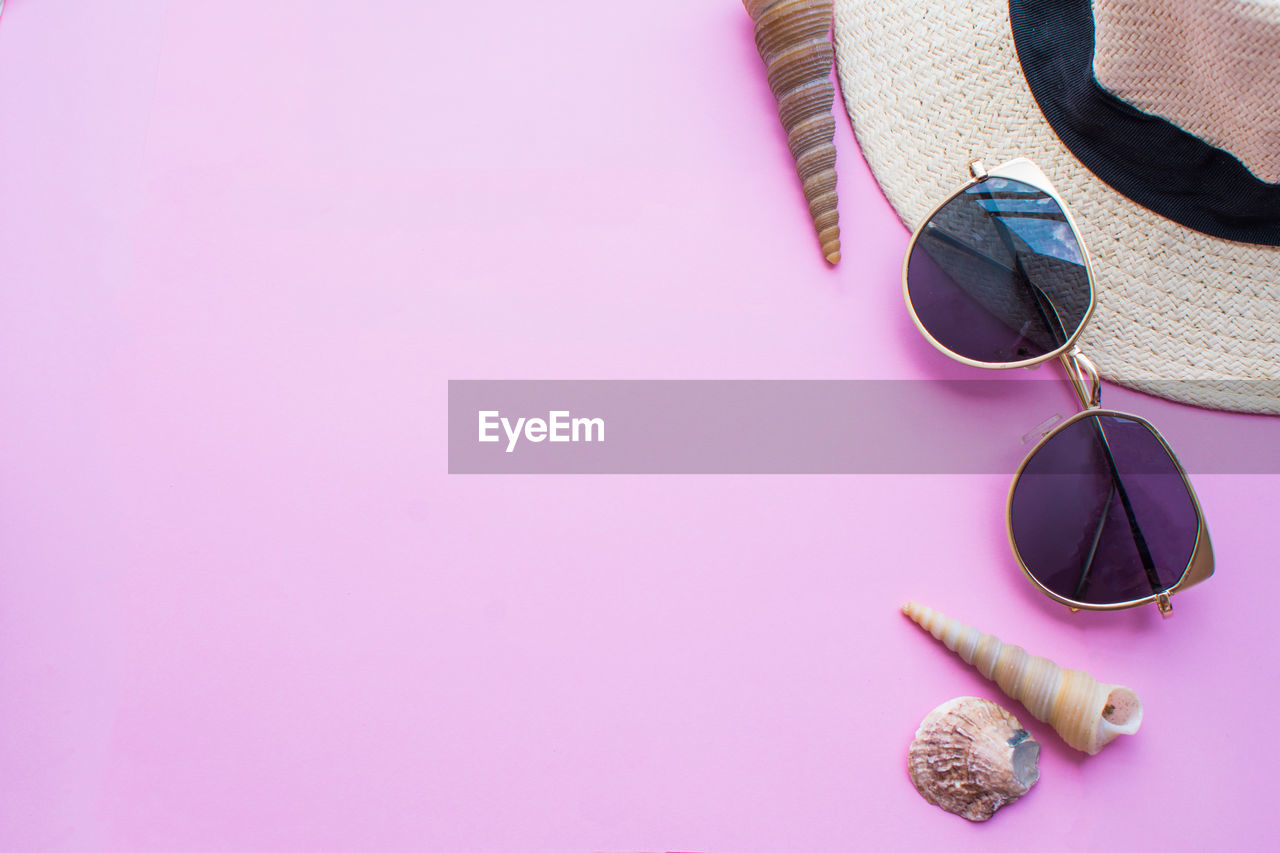 High angle view of sunglasses with hat and seashell on table