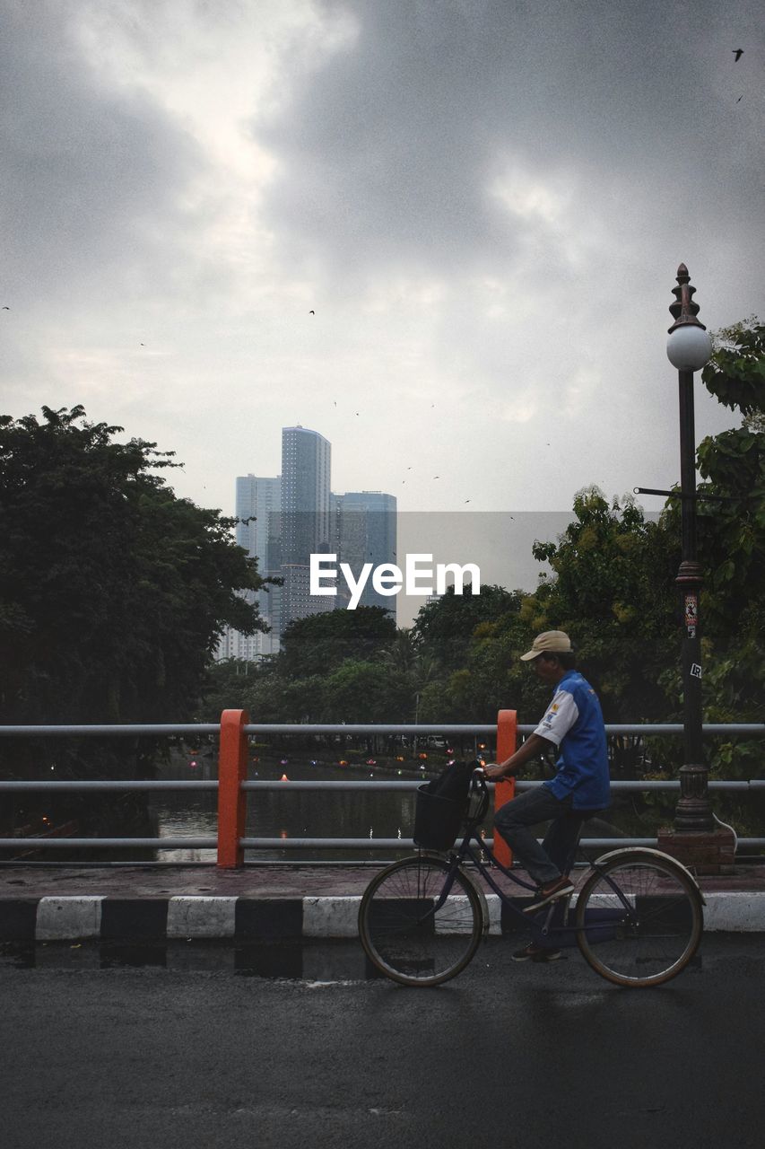 MAN WITH BICYCLE AGAINST CITYSCAPE