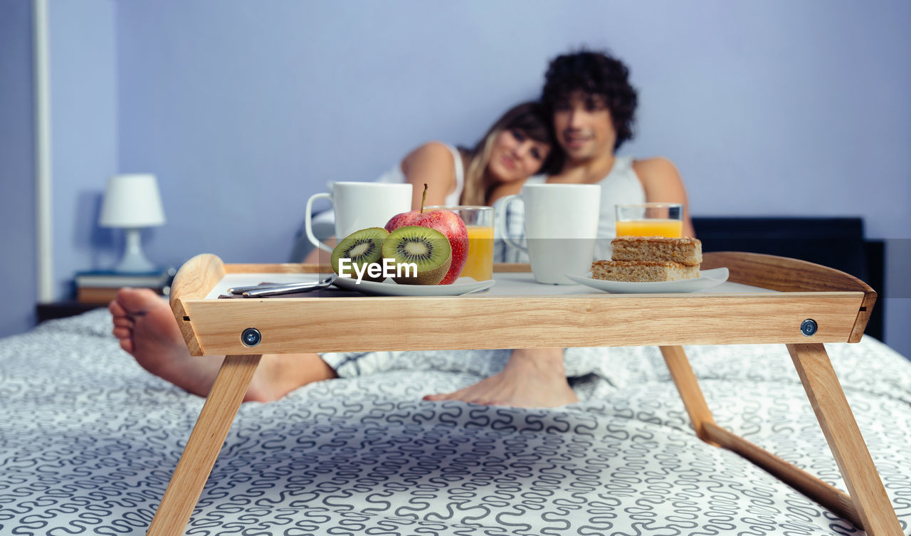 Couple with breakfast on bed at home
