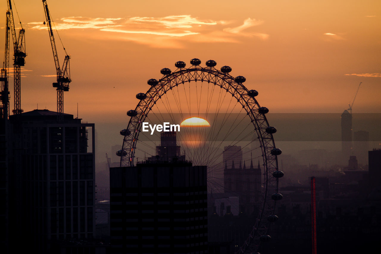 Silhouette ferris wheel against sky in city during sunset