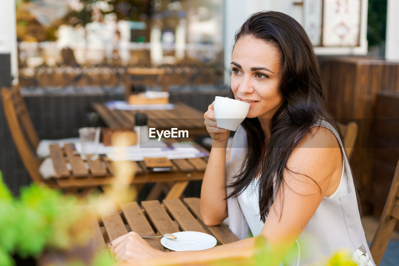 Happy smiling business brunette drinking coffee in a street cafe. coffee break