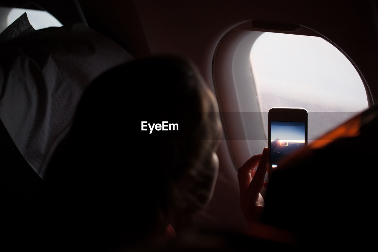 Close-up of woman photographing through airplane window