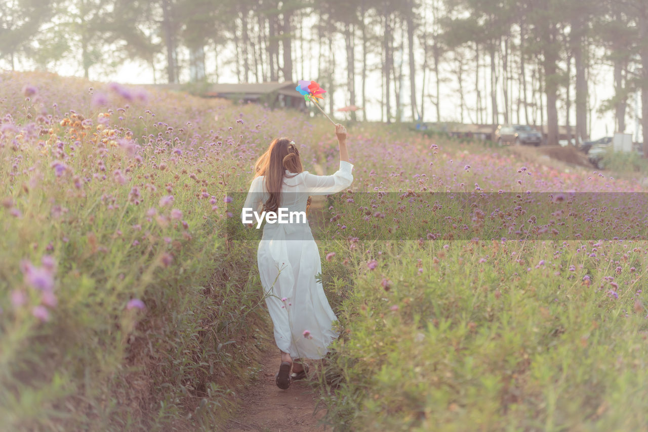 SIDE VIEW OF WOMAN ON FIELD BY FLOWER PLANTS