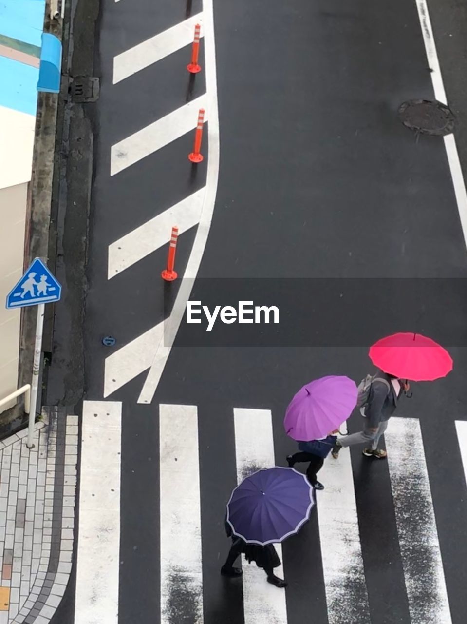 HIGH ANGLE VIEW OF UMBRELLA ON ROAD IN RAIN