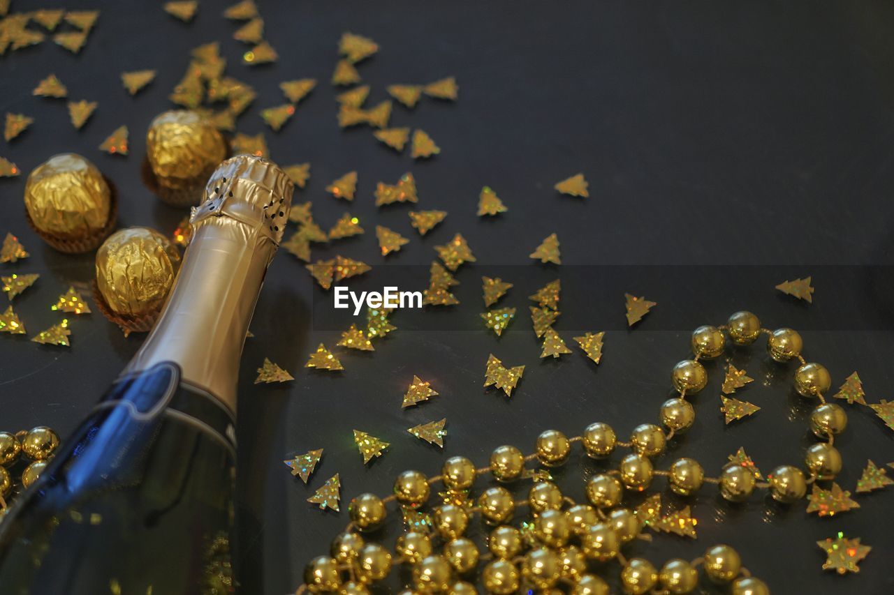 Close-up of wine bottle with golden decorations over black background